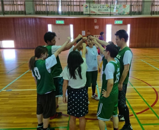 バスケのチームで円になって手を上げている写真