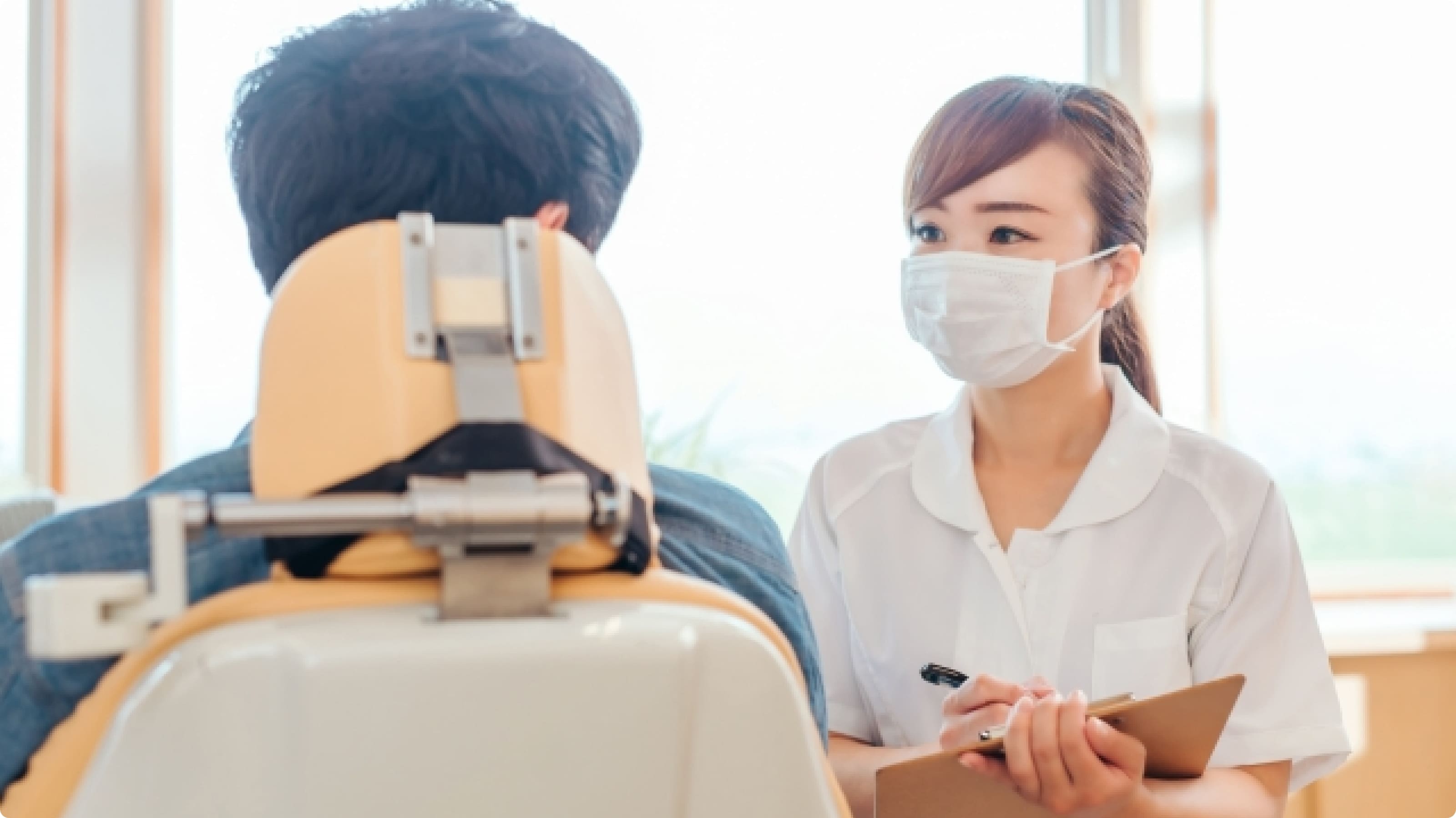 歯科助手が男性患者と診察室で話している写真